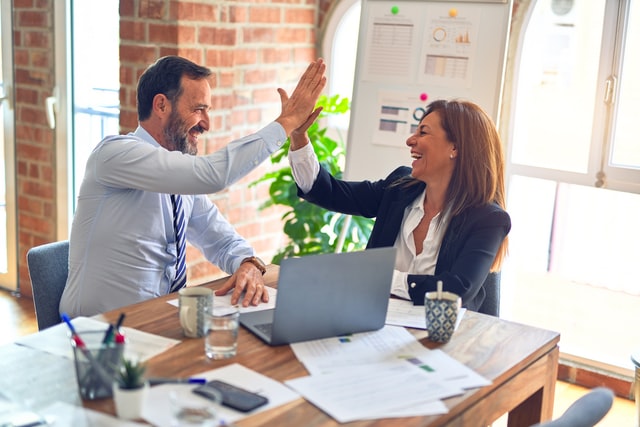 Two officey people high-fiving